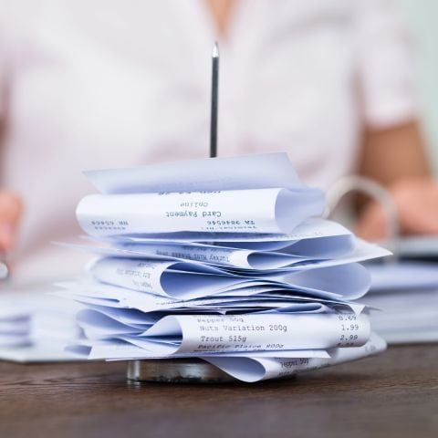 An accountant sitting in front of a stack of receipts.